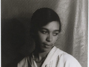 Mildred Johnson Edwards glances to the side, thinly striped pattern behind her.